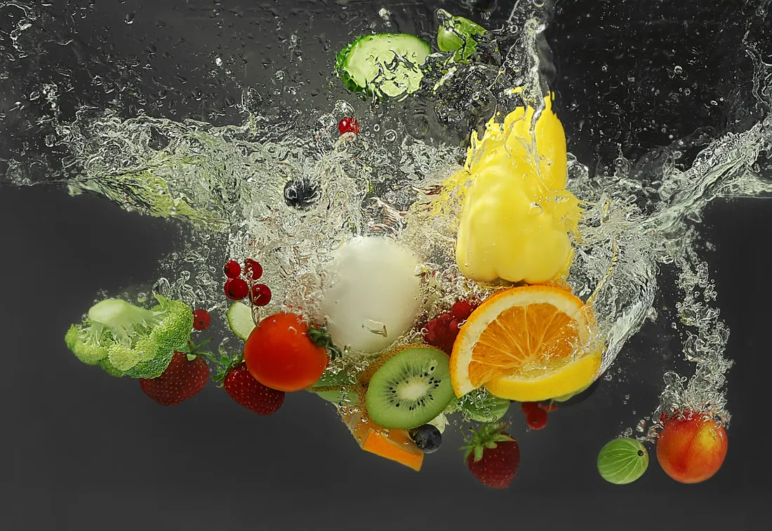 Gemüse und Obst fallen mit Spritzern in klares Wasser – Symbolfoto für das Waschen